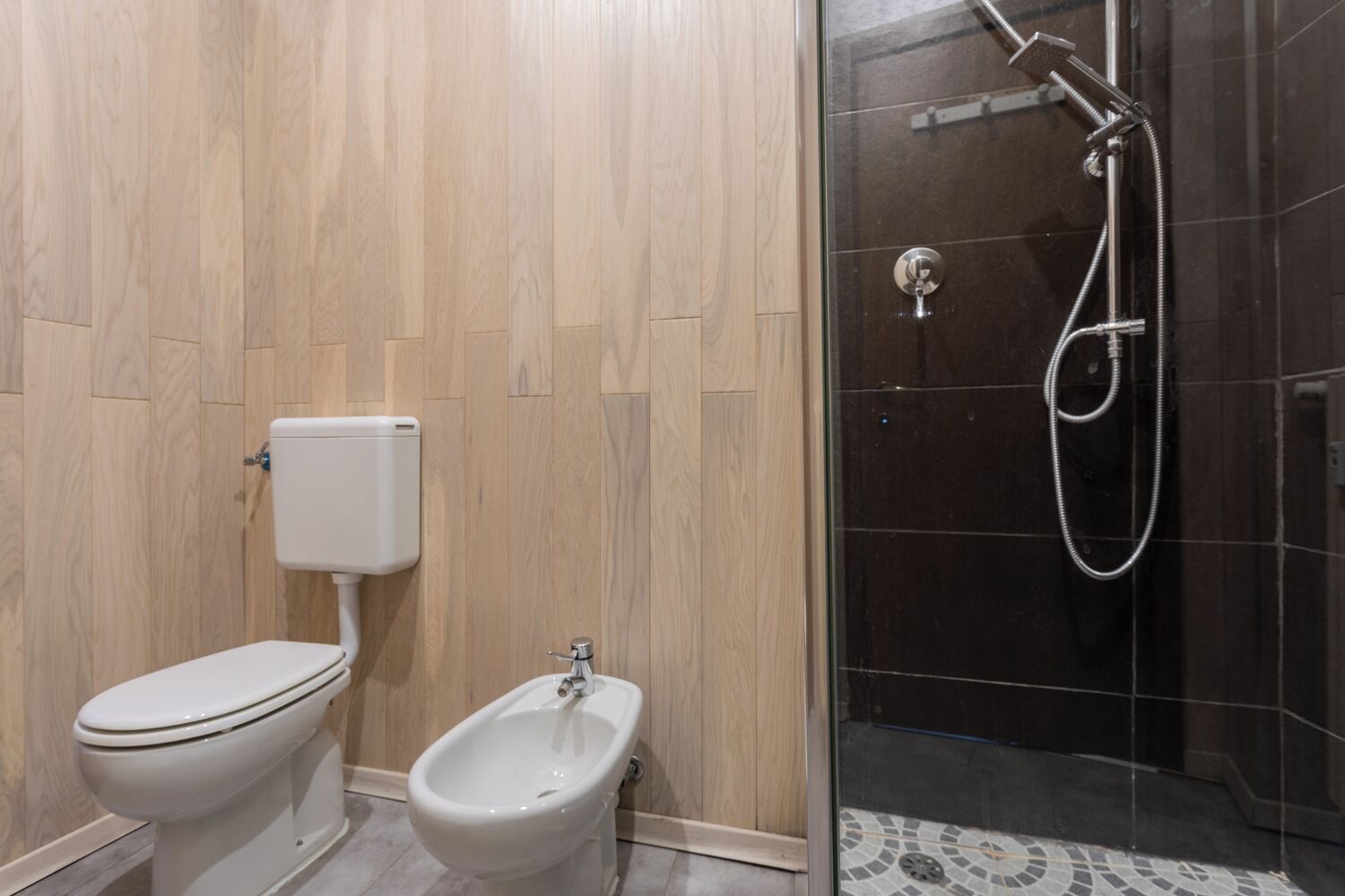 Une salle de bain moderne équipée de toilettes, d’un bidet et d’une douche à parois de verre.