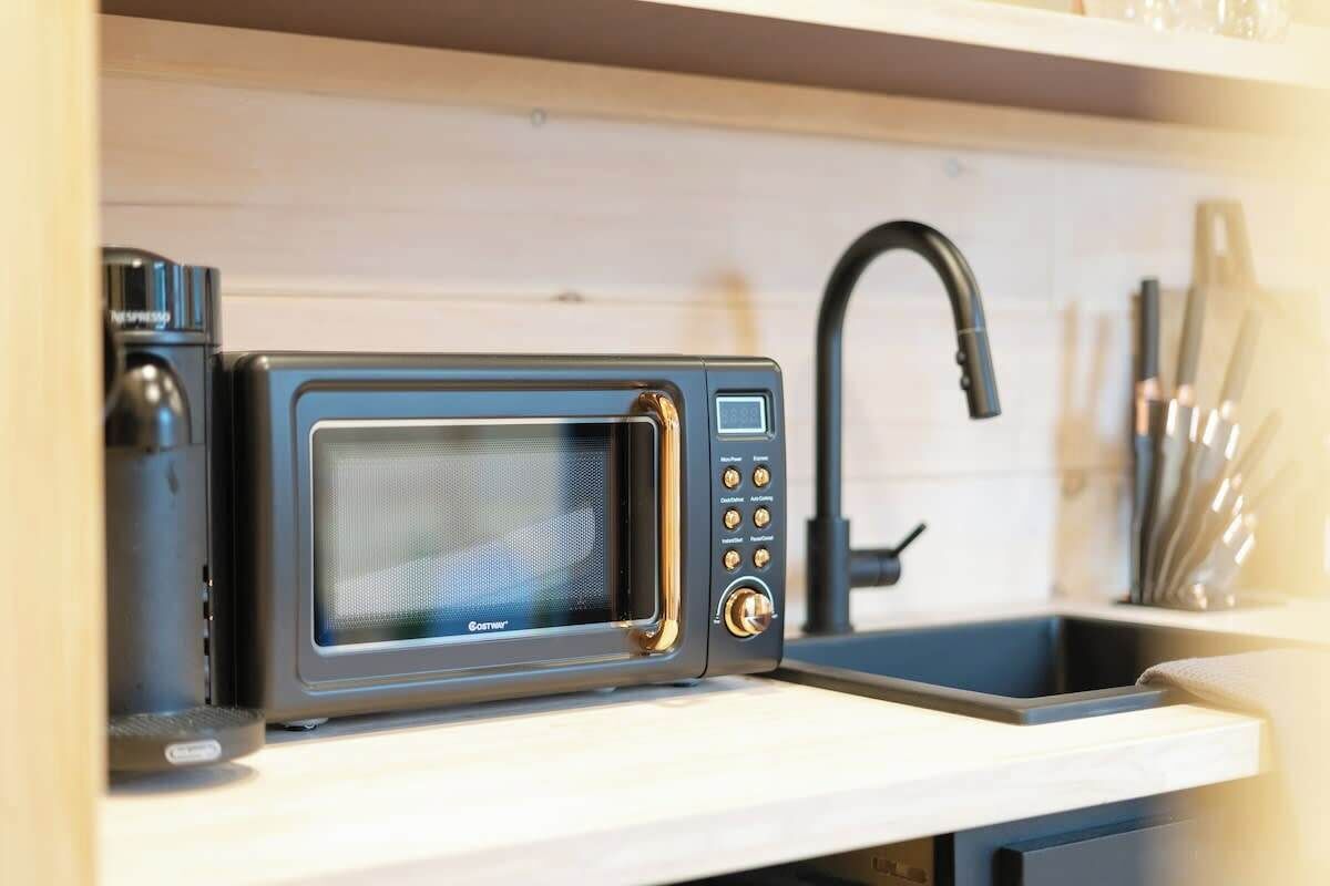 A compact kitchen with a built-in microwave and a modern faucet.