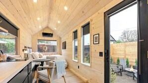 Interior acogedor de una cabaña de madera, con comedor, sofá y vista al jardín.