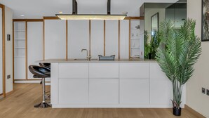 Una cocina moderna con armarios blancos, una isla central con pileta y un taburete de bar.