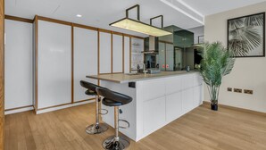 Una cocina moderna con una isla central, taburetes de bar y una planta en maceta.