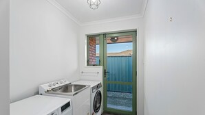 Una sala de lavandería con lavadora, secadora y lavabo.