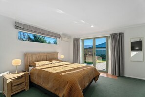 Une chambre avec un grand lit, une table de chevet, une lampe, une fenêtre avec des rideaux et une vue sur l’extérieur.