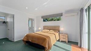 Un dormitorio con una cama grande, lámparas de noche, una ventana y un equipo de aire acondicionado.