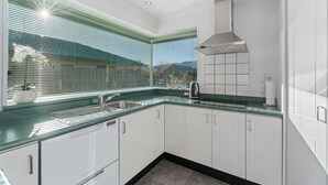 Una cocina moderna con armarios blancos, un lavamanos de acero inoxidable y una encimera verde.