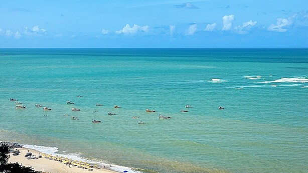 A beach with clear turquoise water, boats, and umbrellas. - Beautiful and cozy flat. Complete and just 50 m from the beach  (Candeias Jaboatão dos Guararapes)