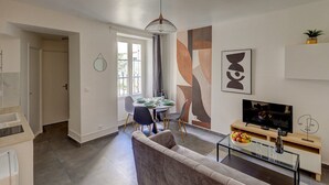 Una sala de estar moderna con un sofá, televisor y un comedor con mesa y sillas.