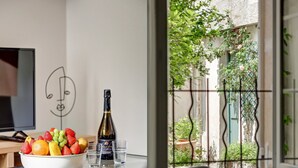 Una habitación con una mesa de comedor, un cuenco de fruta, una botella de vino y un dibujo de un rostro en la pared.