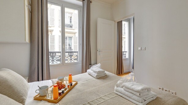 A hotel room with a bed, a breakfast tray, and a view of the outside balcony. - 316 Suite BIOT 5 - Superb apartment in Paris (Paris 17 Batignolles-Monceau)