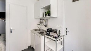 Uma cozinha compacta equipada com fogão, pia e um pequeno balcão com cafeteira e torradeira.