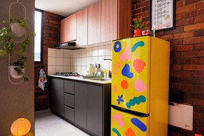 Une cuisine moderne avec un réfrigérateur jaune, des armoires en bois et un mur en briques.