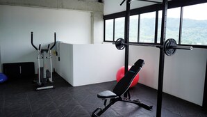 Ein Fitnessstudio mit Langhantelbank, Kniebeugestange und Kurzhantelbank.