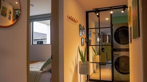 Ein modernes Schlafzimmer mit einem Bett, einem großen Fenster und einer Waschgelegenheit mit Waschmaschine.