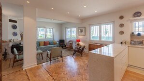 A spacious living area with a fireplace, comfortable seating, and large windows. - FLH Jacaranda Costa Caparica Beach House (Almada)