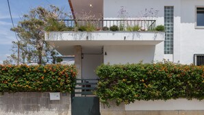 A two-story house with a balcony, a small garden, and a stone wall. - FLH Jacaranda Costa Caparica Beach House (Almada)
