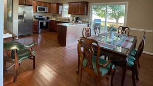 A spacious kitchen with wooden cabinets, a refrigerator, and a dining area with a table and chairs.