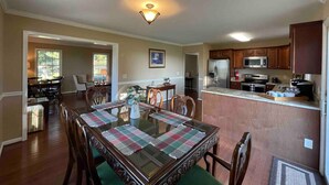 A dining area with a table set for four, a kitchen with modern appliances, and a hallway leading to another room.