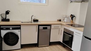 Une cuisine compacte équipée d’un lave-linge, d’un lave-vaisselle, d’un four et d’une fenêtre située au-dessus de l’évier.