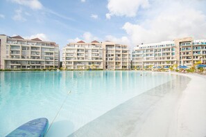 A large swimming pool with a clear blue water surface, surrounded by multi-story hotel buildings with balconies. - U-GO Baia Kristal. Oasis en Cartagena (Cartagena)