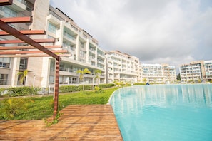 Un hôtel moderne doté d’une grande piscine, de nombreux balcons et d’une végétation luxuriante.