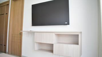 Una habitación con un armario de madera, un cuadro con marco negro y una estantería de madera clara.