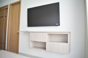 Une pièce avec une armoire en bois, un tableau encadré de noir et une étagère en bois clair.