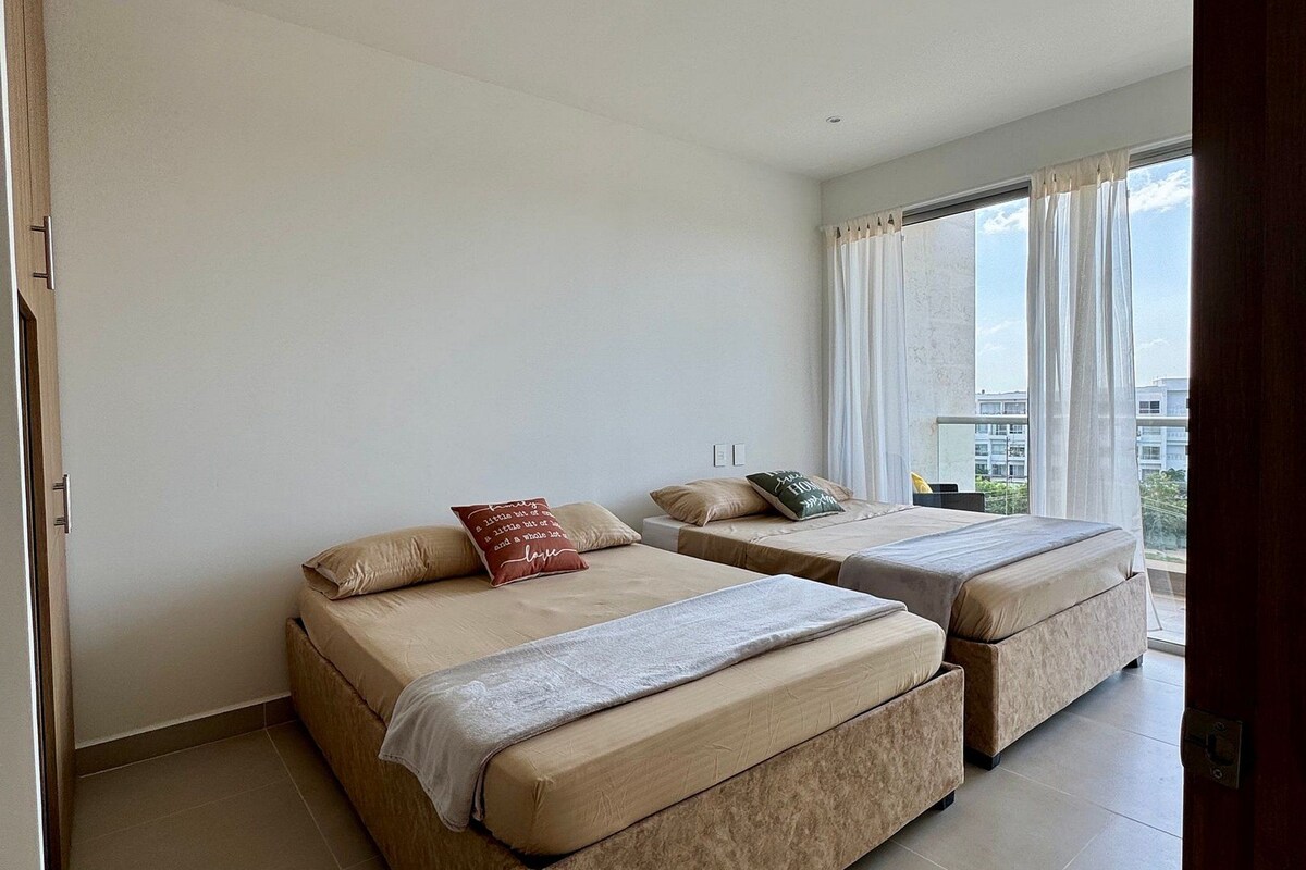 A hotel room with two beds, a large window, and a view of the city.