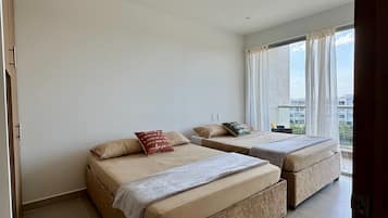 Quarto de hotel com duas camas, uma janela grande e vista para a cidade.