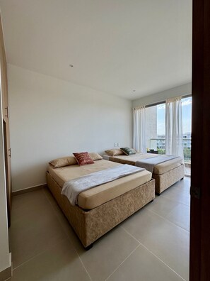 Ein Hotelzimmer mit zwei Betten, einem großen Fenster und Blick auf die Stadt.