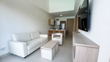 Uma sala de estar moderna com um sofá branco, uma mesa de centro e uma TV fixada na parede.