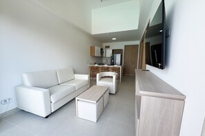 Ein modernes Wohnzimmer mit einem weißen Sofa, einem Couchtisch und einem an der Wand befestigten Fernseher.