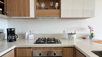 Una cocina moderna con armarios de madera, horno empotrado, estufa a gas y cafetera.