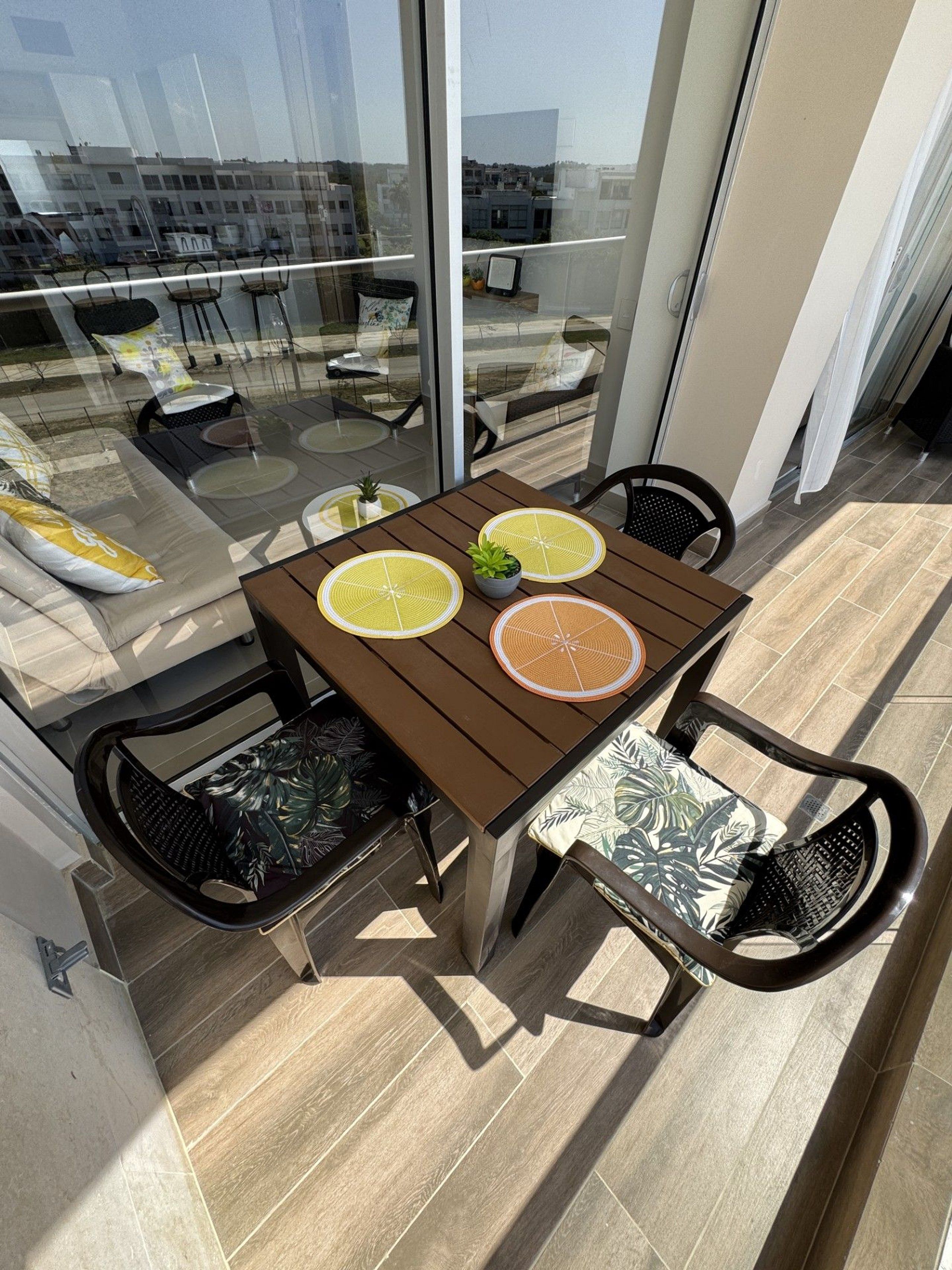 Uma varanda com mesa, cadeiras e vista para a paisagem urbana.