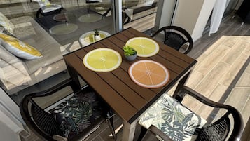 Uma varanda com mesa, cadeiras e vista para a paisagem urbana.