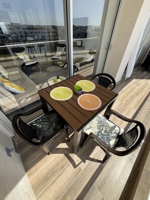 Ein Balkon mit Tisch, Stühlen und Blick auf die Stadt.
