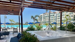 A poolside area with a hot tub, lounge chairs, and umbrellas.