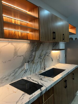 Una cocina moderna con encimeras de mármol, armarios de madera integrados e iluminación debajo de los armarios.