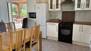 A compact kitchen with a dining table and chairs, a refrigerator, a microwave, a stove, and cabinets.