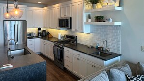 A modern kitchen with white cabinets, stainless steel appliances, and a granite countertop. - New! 3-bedroom lake-front condo on Flathead Lake (Polson)
