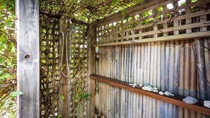 A wooden fence with a bamboo panel, a wooden post, and a shelf with seashells. - 8 Sunnyside Crescent Kianga (Kianga)