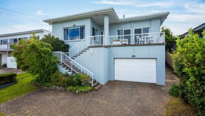 A two-story house with a front staircase, a garage, and a balcony with outdoor seating. - 8 Sunnyside Crescent Kianga (Kianga)