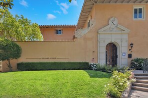 A building with a well-maintained lawn, a decorative entrance, and a clear sky. - Westholme Park (Los Angeles)