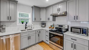 A modern kitchen with grey cabinets, a built-in oven, microwave, and a coffee machine. - Cityscape (Chelsea)