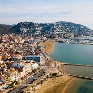 A coastal cityscape with a beach, buildings, and a hilly background. - Norfeu Park 2-4 in Roses (Roses)