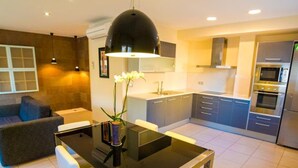 A modern kitchen with a central island, white chairs, and a pendant light.