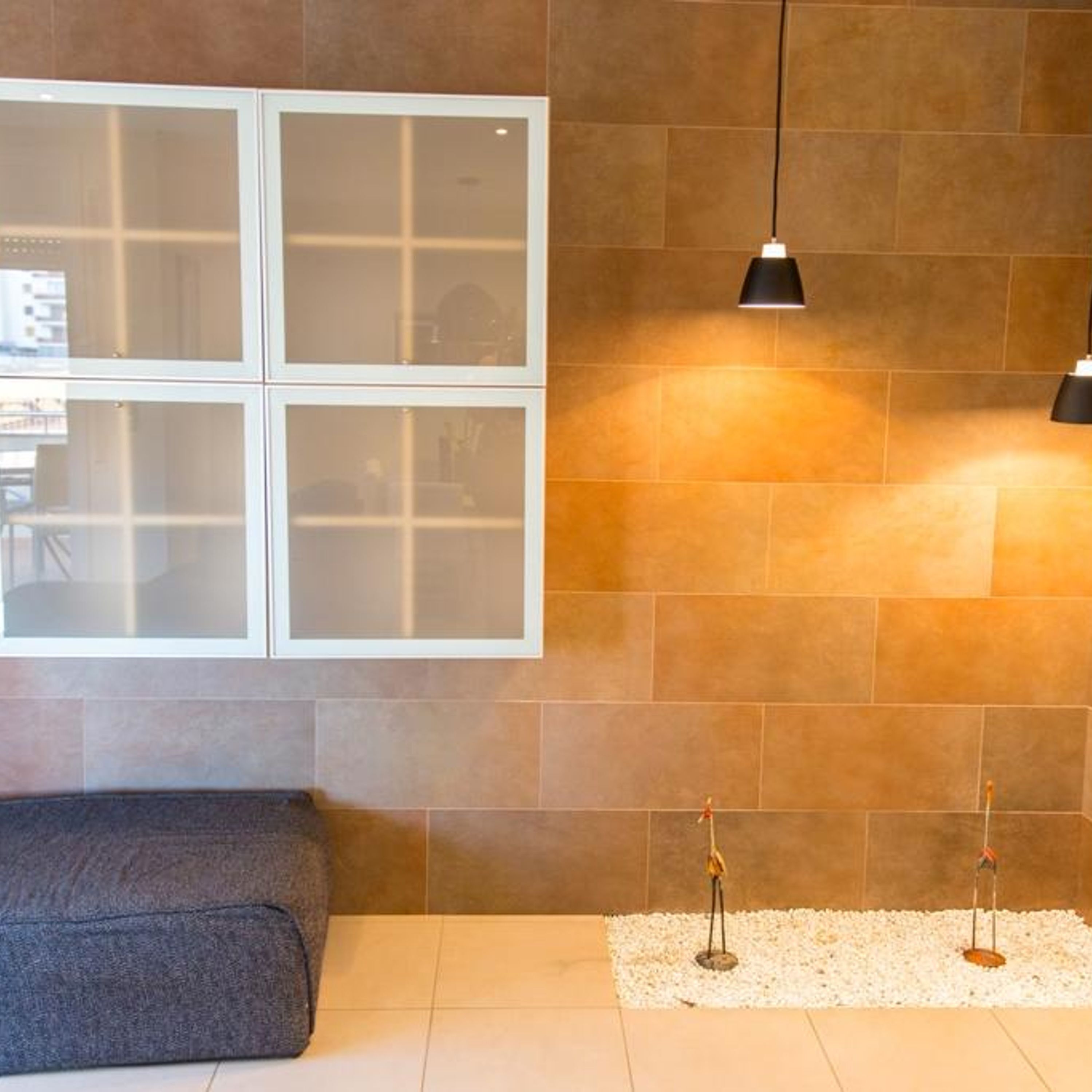 A modern interior with a large frosted window, a gray sofa, and two pendant lights.