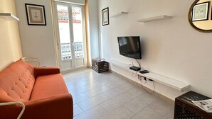 A living room with a sofa, a television, and a door leading to a balcony. - Joan Badosa 1 A in Roses (Roses)