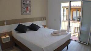 A hotel room with a large bed, a nightstand, a wall-mounted light, and a sliding glass door leading to an outdoor area. - Cosconilles 2 in Roses (Roses)