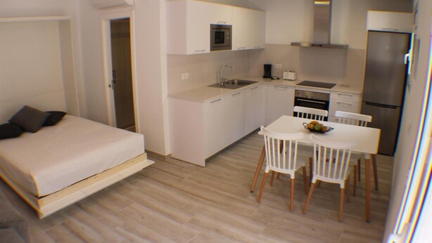 Ein kleines Zimmer mit Bett, Küchenzeile und Essbereich.