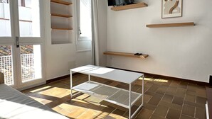 A modern room with a white table, shelves, and a TV on the wall. - Porthos 111 in Roses (Roses)